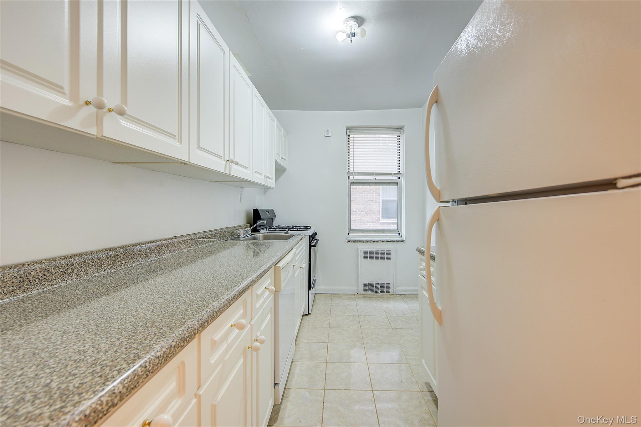 67-12 Yellowstone Boulevard, Unit D9 Queens, NY 11375 - Photo 17 of 36 a view of a kitchen with white cabinets and refrigerator