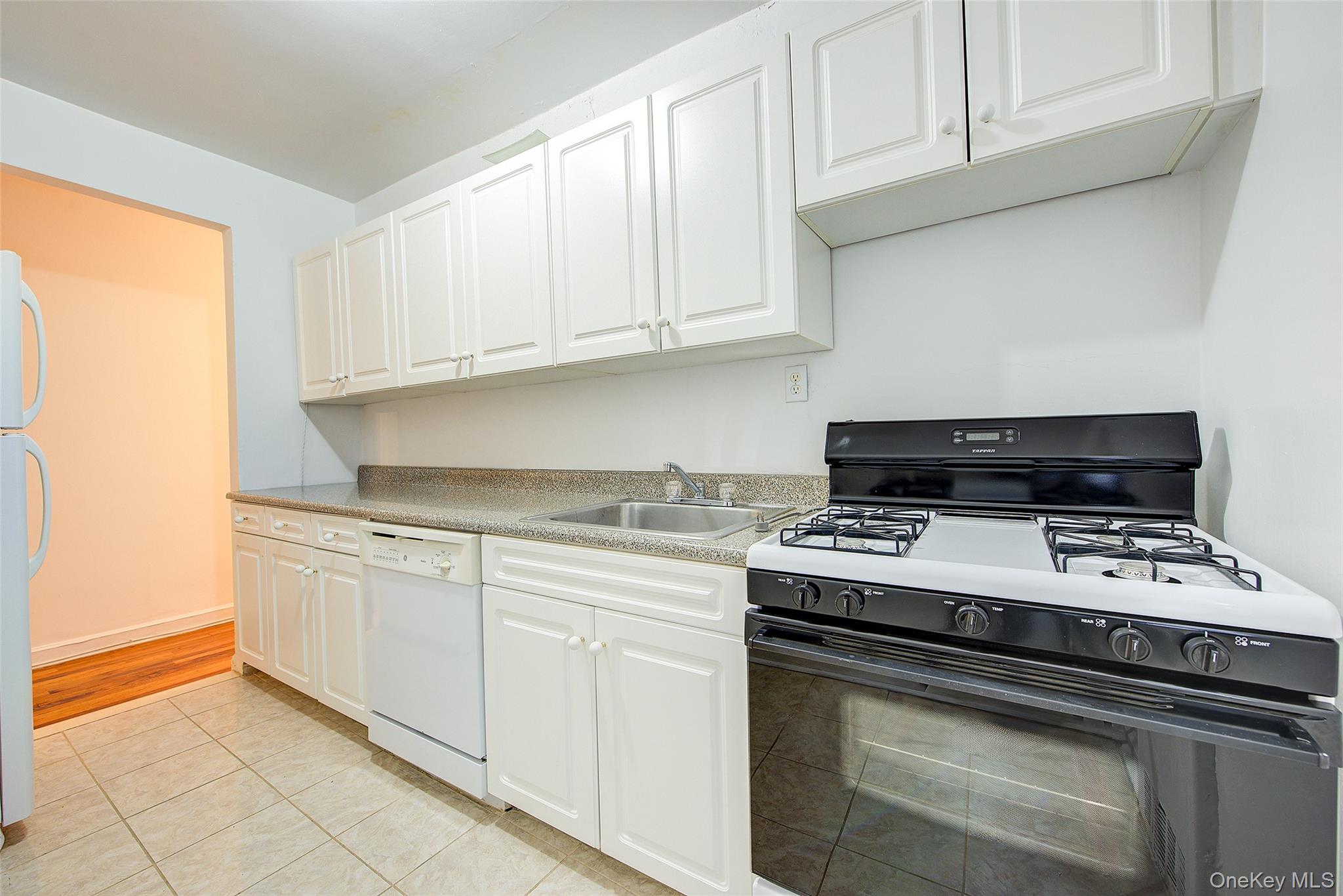 67-12 Yellowstone Boulevard, Unit D9 Queens, NY 11375 - Photo 18 of 36 a kitchen with granite countertop white cabinets and black appliances