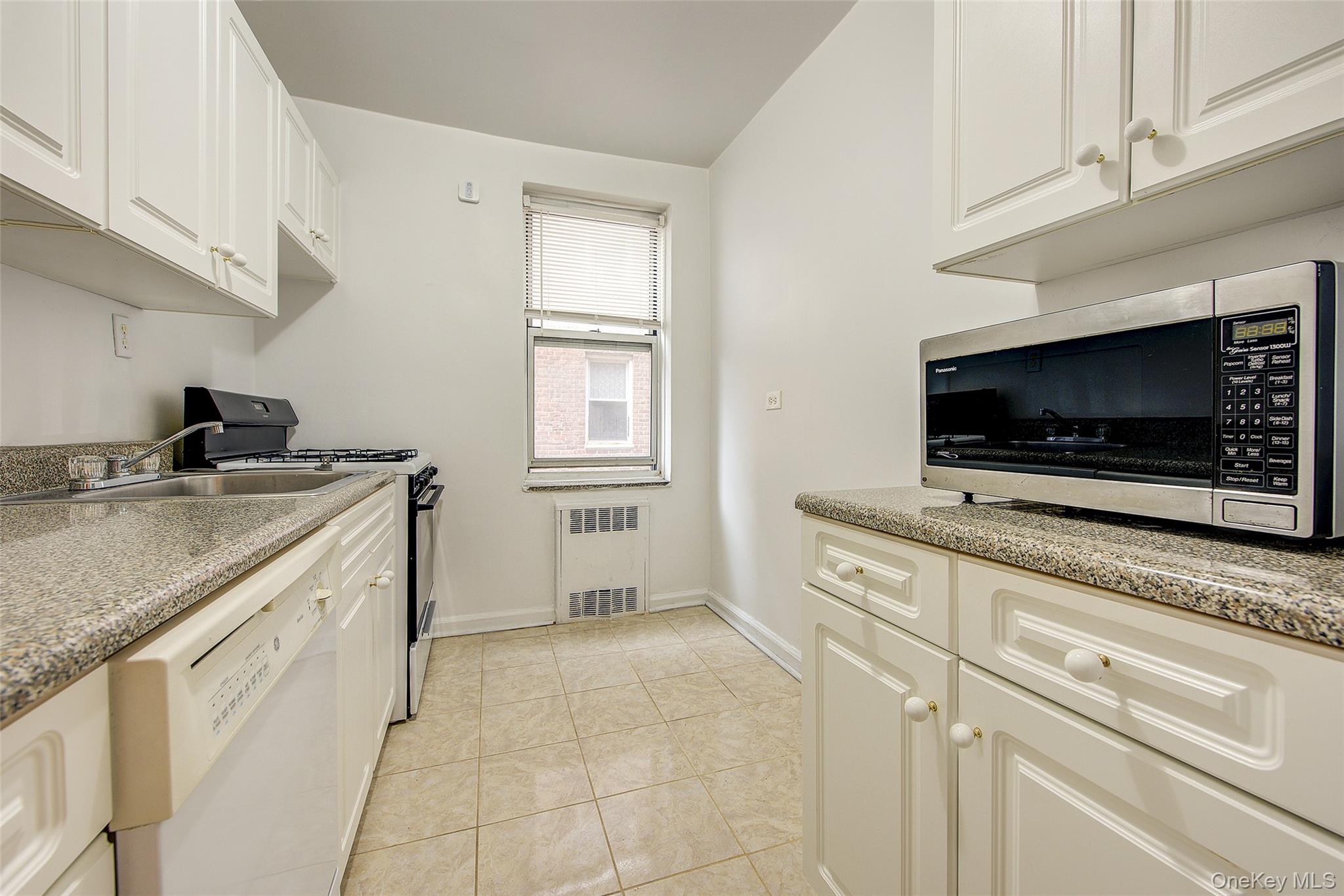 67-12 Yellowstone Boulevard, Unit D9 Queens, NY 11375 - Photo 19 of 36 a kitchen with granite countertop white cabinets stainless steel appliances and sink