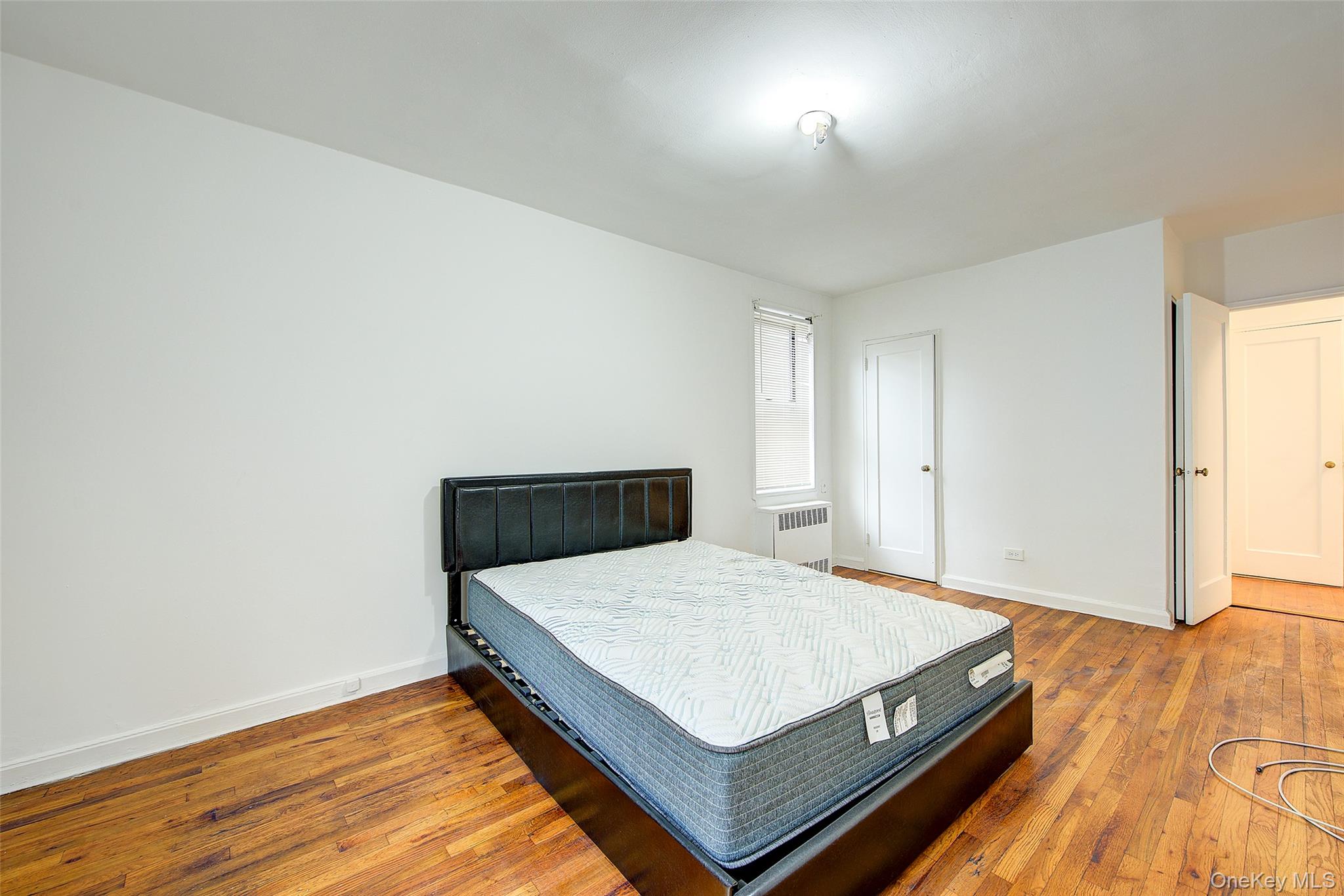 67-12 Yellowstone Boulevard, Unit D9 Queens, NY 11375 - Photo 21 of 36 a bedroom with a bed and wooden floor