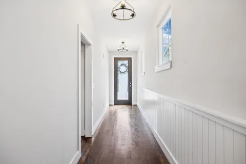 a view of a hallway with wooden floor and a chandelier