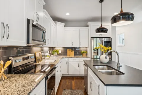 a kitchen with stainless steel appliances granite countertop a sink a stove and a wooden floor