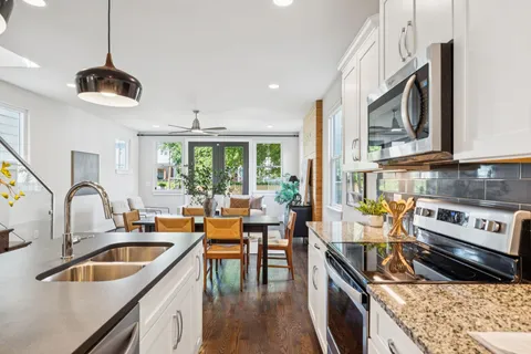 a kitchen with stainless steel appliances a stove a sink and white cabinets