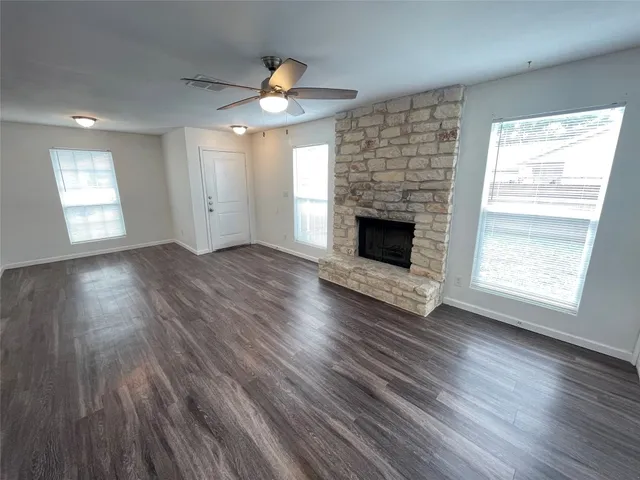 an empty room with wooden floor fireplace and windows