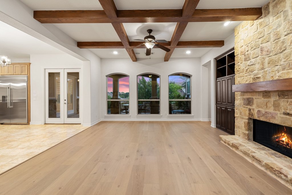 109 Largo Cove Austin, TX 78734 - Photo 7 of 40 Exposed wood beams frame the ceiling of this luminous great room, complemented by a stone-faced fireplace.