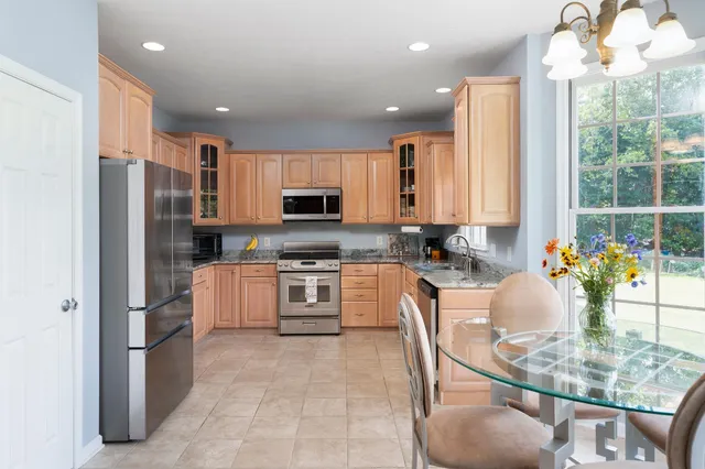 a kitchen with kitchen island granite countertop a stove a sink a refrigerator and white cabinets with wooden floor