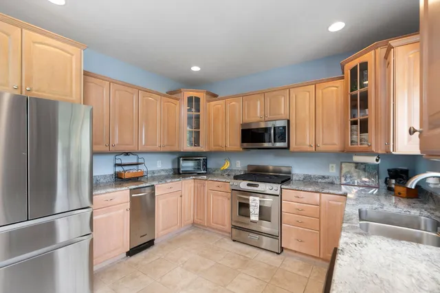 a kitchen with stainless steel appliances granite countertop a refrigerator stove top oven a sink and dishwasher