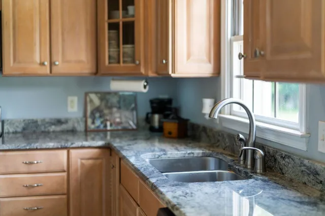 a kitchen with granite countertop a sink a window and cabinets
