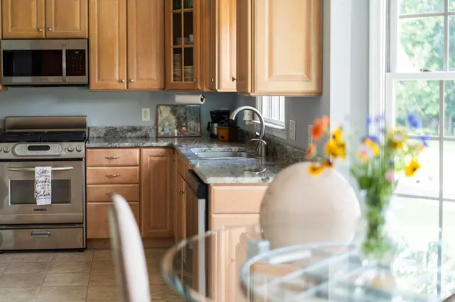 a kitchen with stainless steel appliances granite countertop a stove a sink and a white cabinets