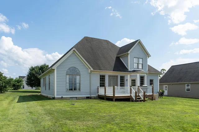 a view of a house with a big yard potted plants and a large tree