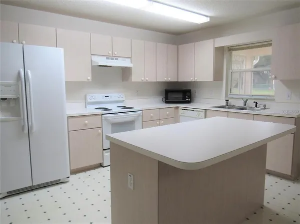 a kitchen with stainless steel appliances a sink a stove a refrigerator and cabinets