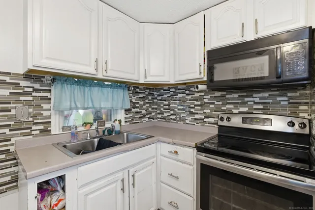 a kitchen with stainless steel appliances white cabinets and a stove top oven