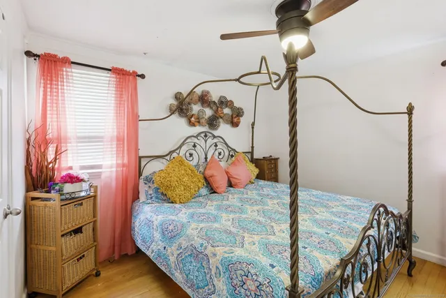 a bedroom with a bed a dresser and potted plants