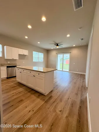 a view of a kitchen with kitchen island a sink wooden floor and a counter top space