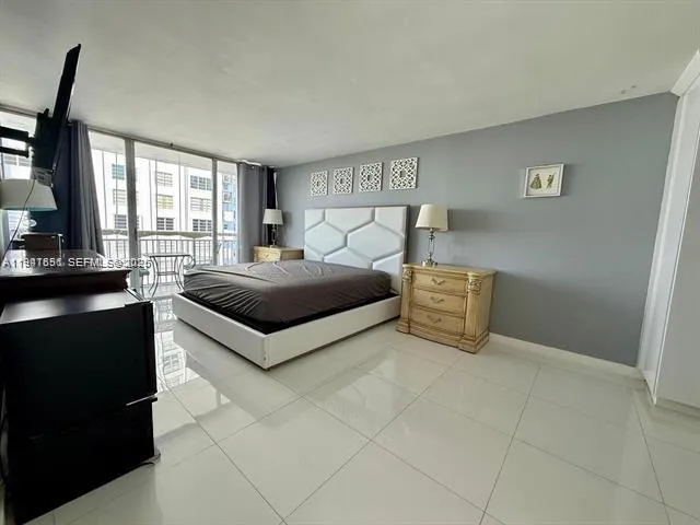 a spacious bedroom with a bed and a flat screen tv
