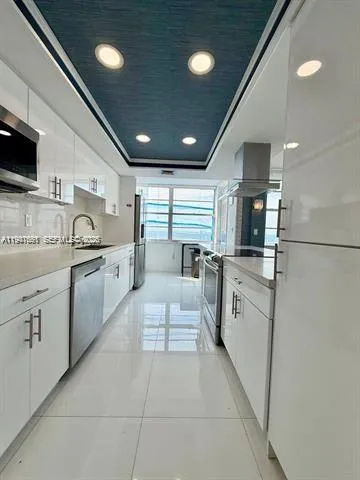 a large white kitchen with a stove top oven a sink and dishwasher