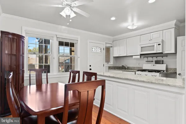 a kitchen with kitchen island granite countertop a dining table chairs refrigerator and cabinets
