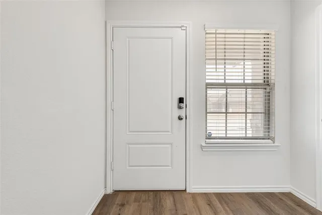 an empty room with wooden floor closet and windows