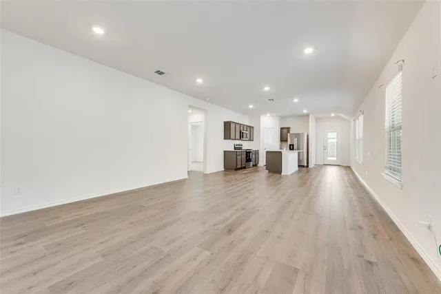 a kitchen with sink a microwave oven a refrigerator with white cabinets and wooden floor