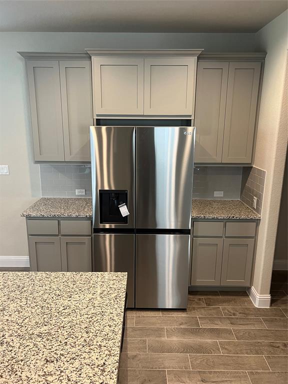 128 Free Stone Drive Georgetown, TX 78628 - Photo 25 of 29 Stainless steel refrigerator integrated with gray shaker cabinetry and speckled countertops