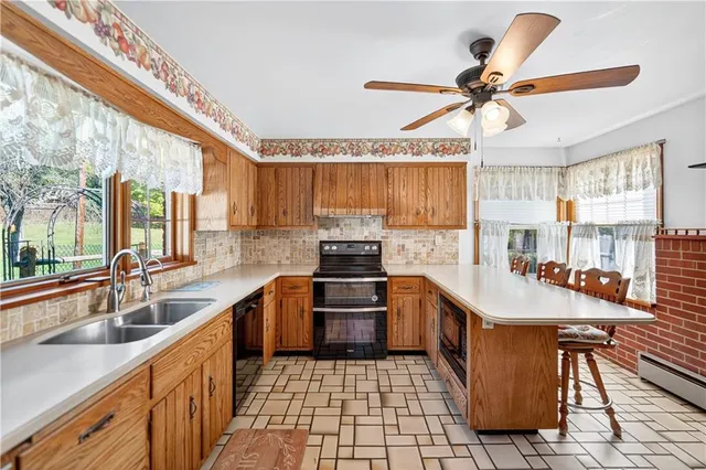 a kitchen with kitchen island granite countertop a sink appliances cabinets and a large window