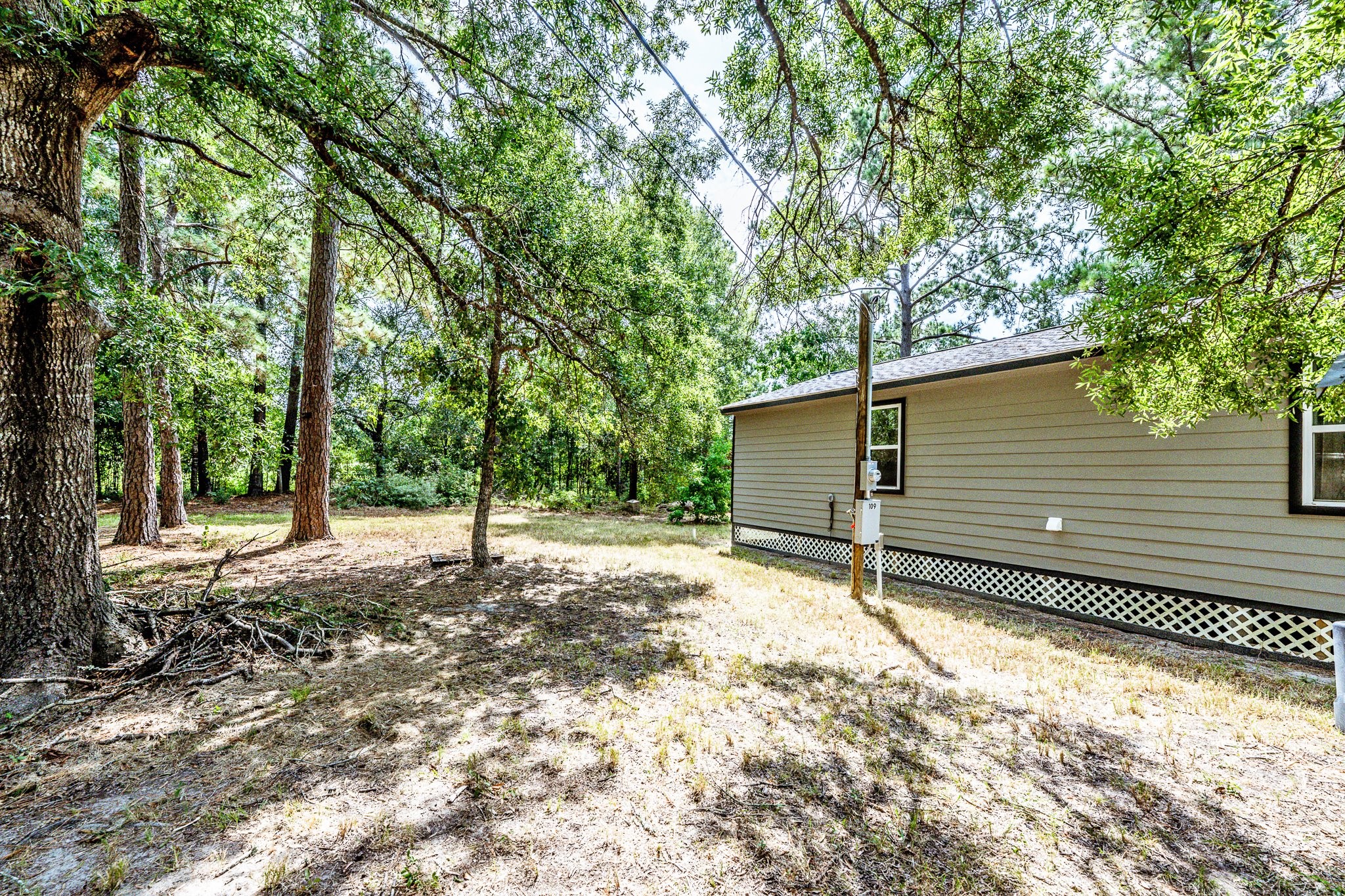 109 Monica Street Trinity, TX 75862 - Photo 29 of 32 a backyard of a house with large trees and a wooden fence