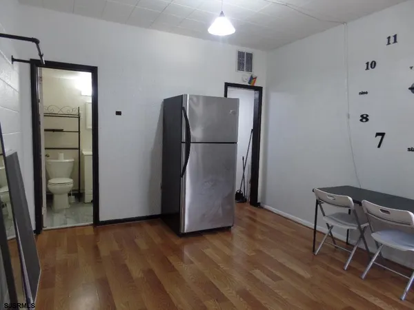a view of a kitchen with refrigerator and wooden floor