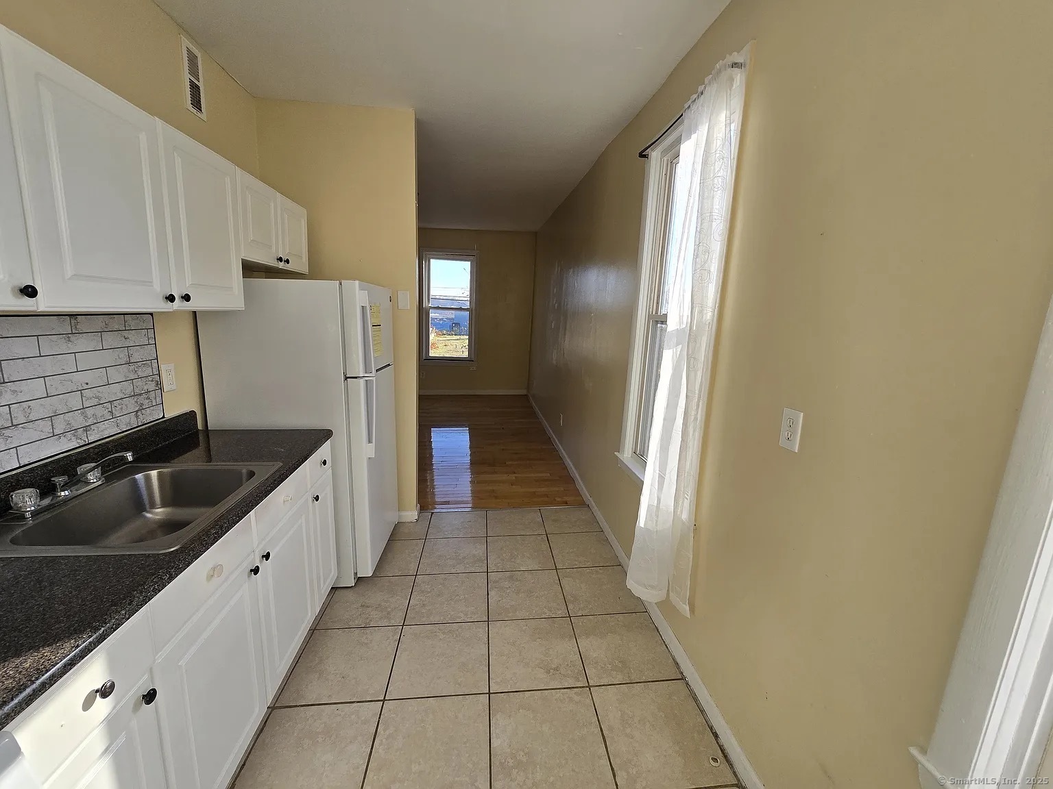 a kitchen with granite countertop white cabinets and refrigerator