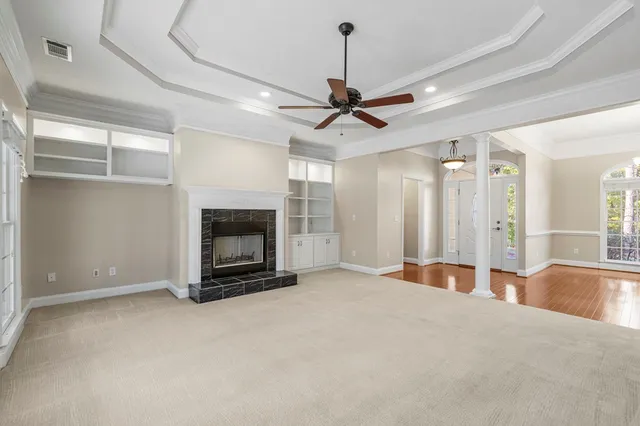 a view of a livingroom with a fireplace a ceiling fan and windows