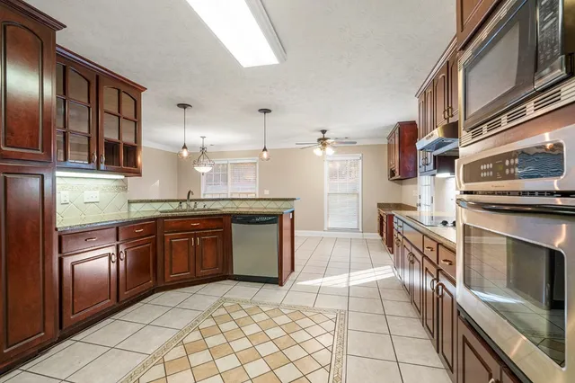 a kitchen with stainless steel appliances granite countertop a refrigerator and a stove top oven