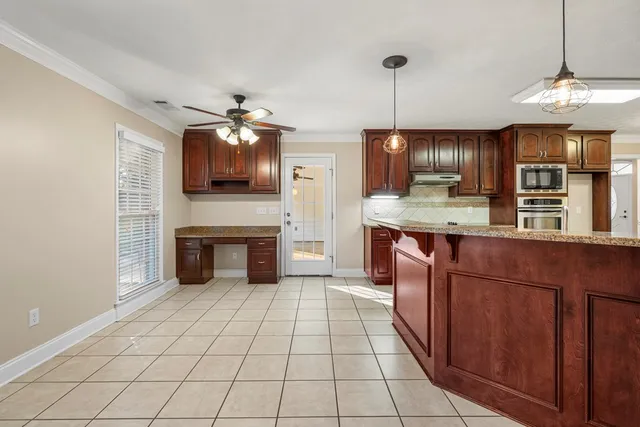 a kitchen with kitchen island granite countertop a stove a sink and a microwave