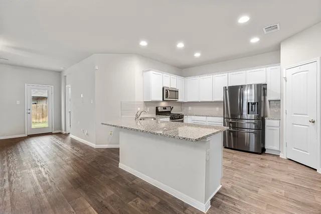 a kitchen with stainless steel appliances granite countertop a refrigerator and a stove top oven