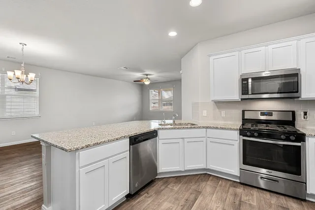 a kitchen with granite countertop a sink stainless steel appliances and white cabinets