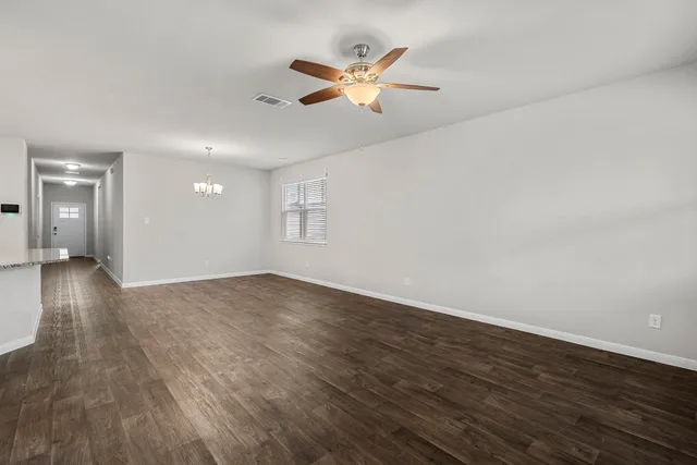 an empty room with wooden floor fan and windows