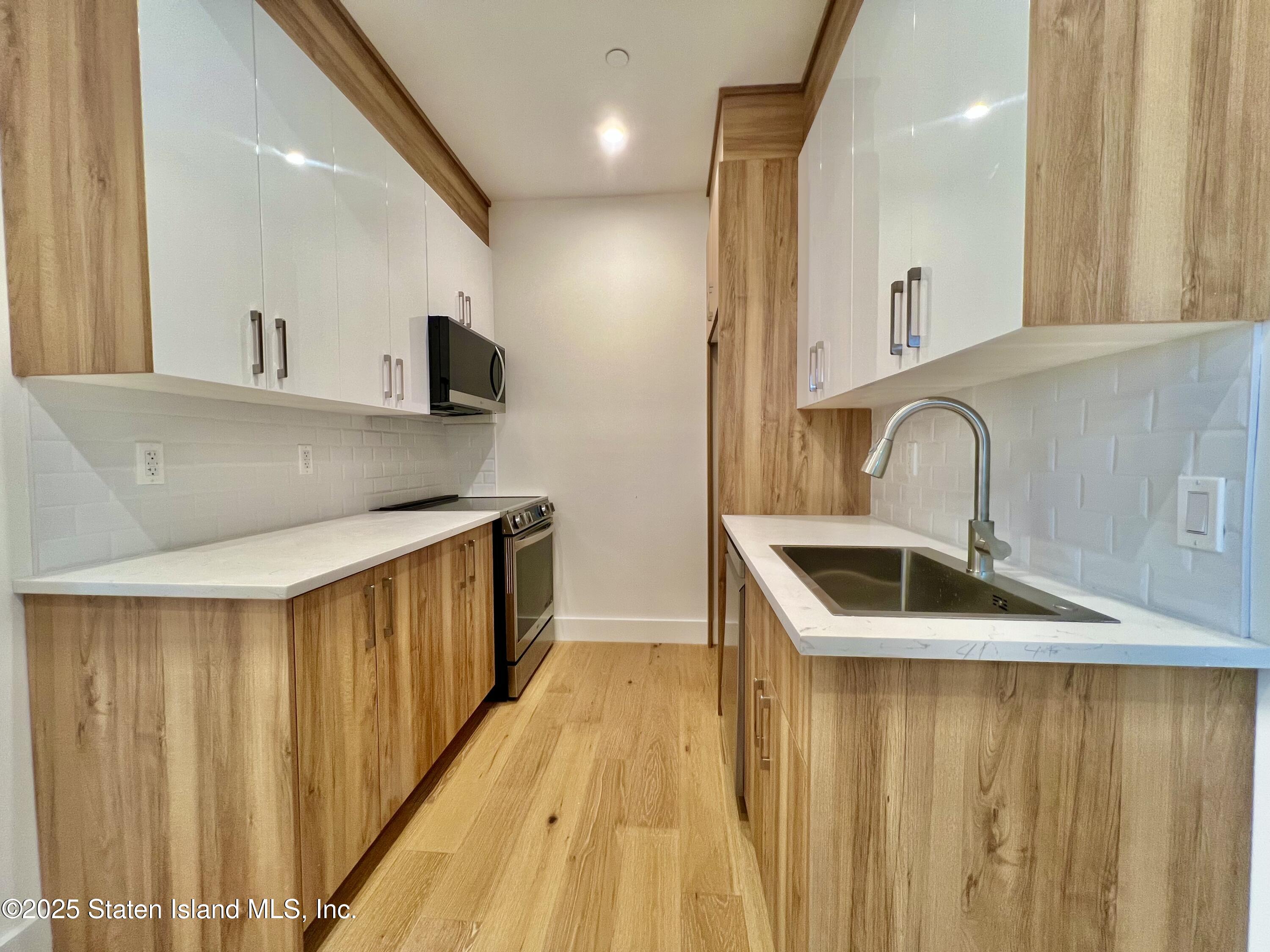 3865 Amboy Road, Unit 2G Staten Island, NY 10308 - Photo 11 of 27 a kitchen with stainless steel appliances a sink and a refrigerator