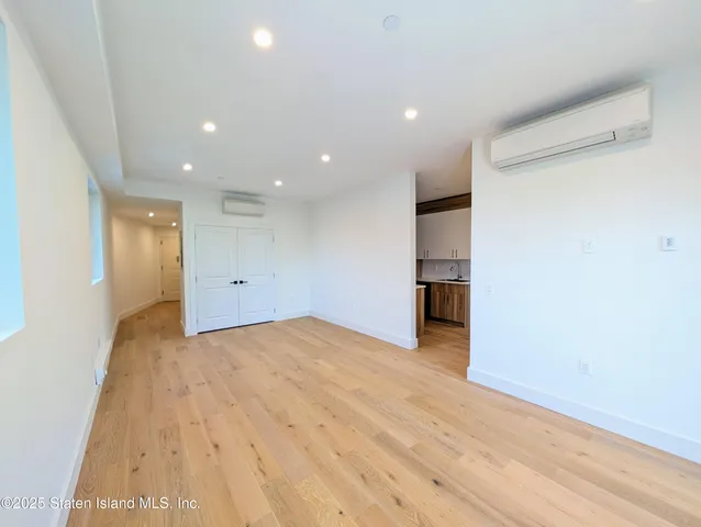 a view of an empty room with wooden floor and closet