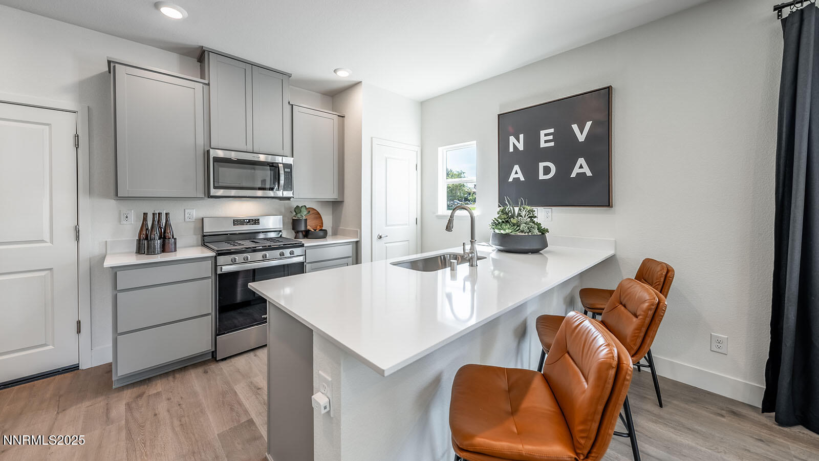 5857 Morgan Horse Street Reno, NV 89523 - Photo 11 of 23 a kitchen with stainless steel appliances granite countertop a stove top oven a sink a refrigerator and white cabinets with wooden floor