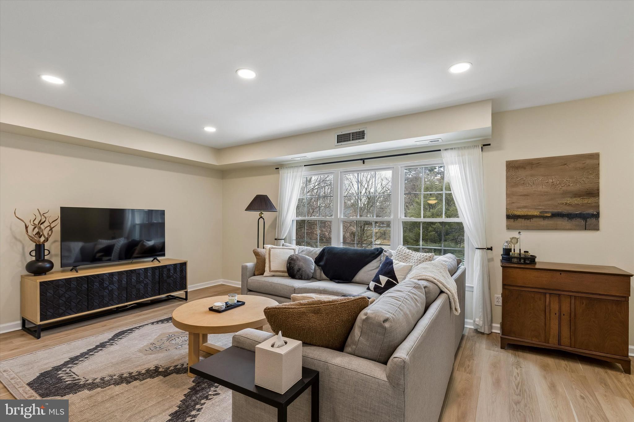 437 Old Forge Crossing, Unit 437 Devon, PA 19333 - Photo 4 of 22 a living room with furniture a flat screen tv and a floor to ceiling window