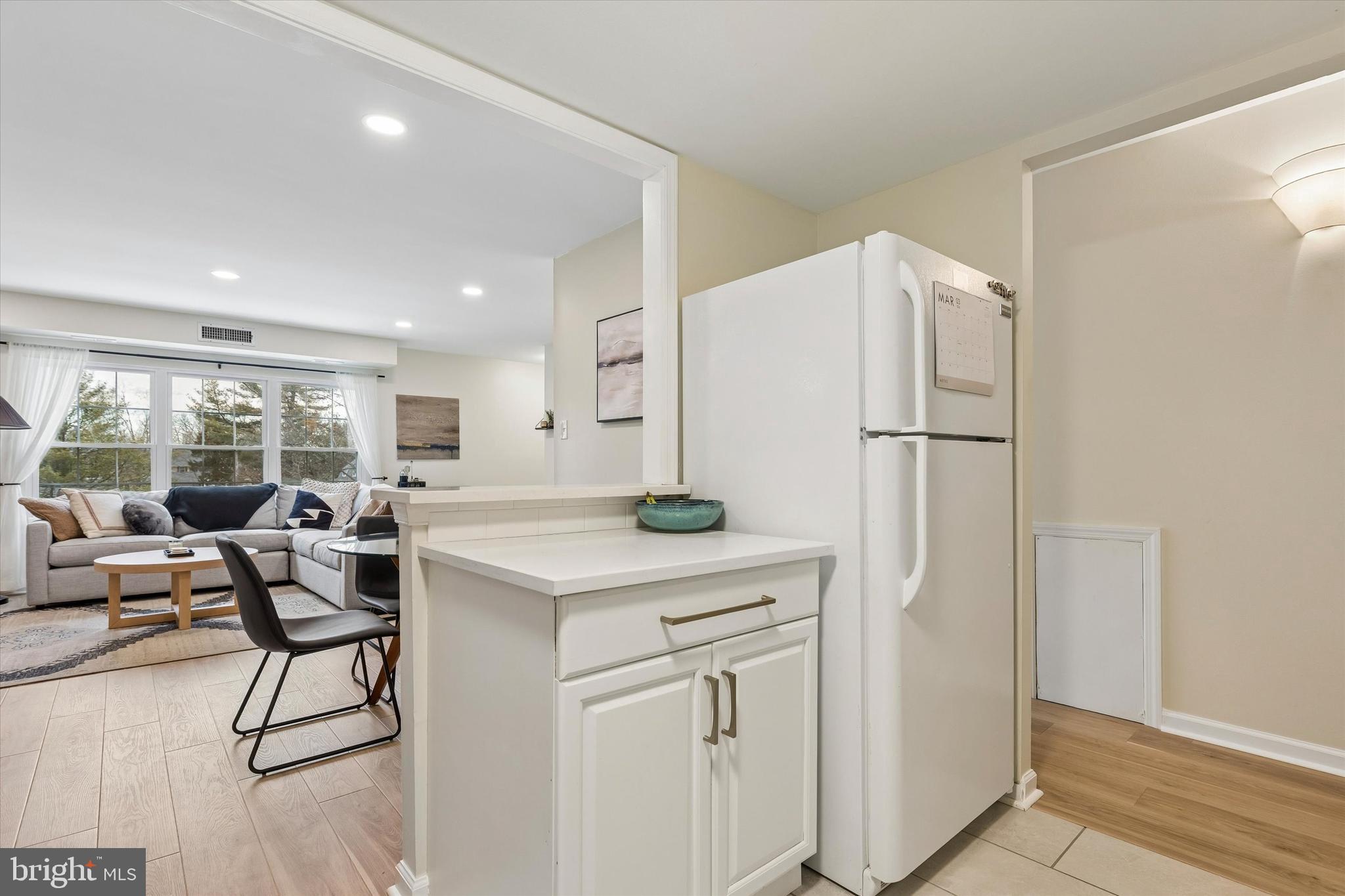 437 Old Forge Crossing, Unit 437 Devon, PA 19333 - Photo 10 of 22 a kitchen with a refrigerator a stove and white cabinets with wooden floor