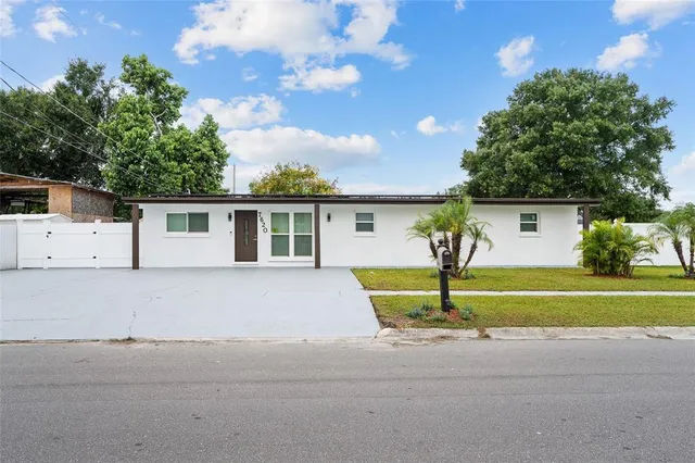 a view of house in front of a big yard with large trees