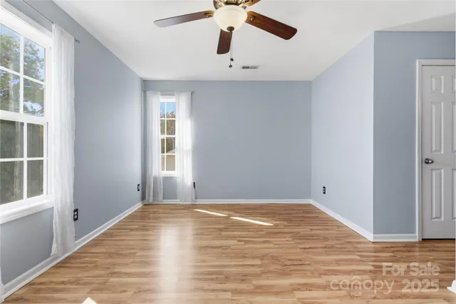 a view of empty room with wooden floor and fan