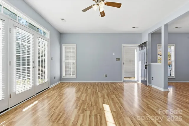 a view of empty room with wooden floor and fan