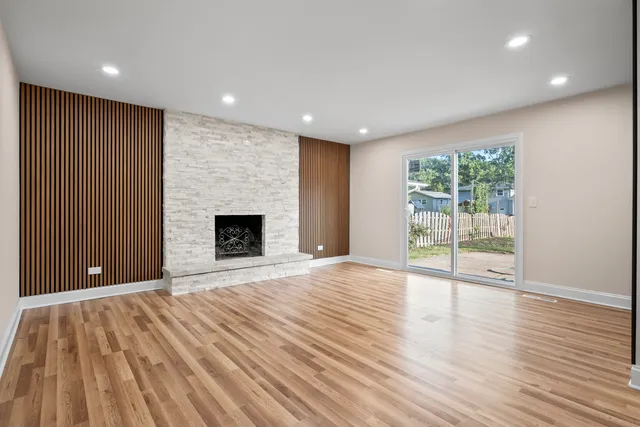 an empty room with wooden floor and a fireplace