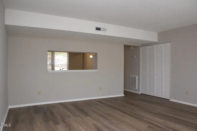 a view of an empty room with wooden floor and a window