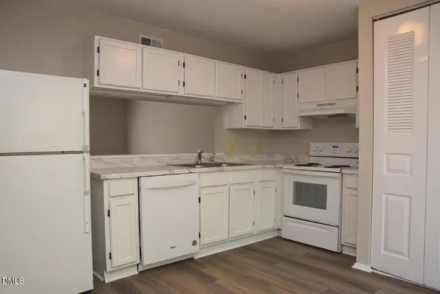 a kitchen with granite countertop white cabinets and white appliances