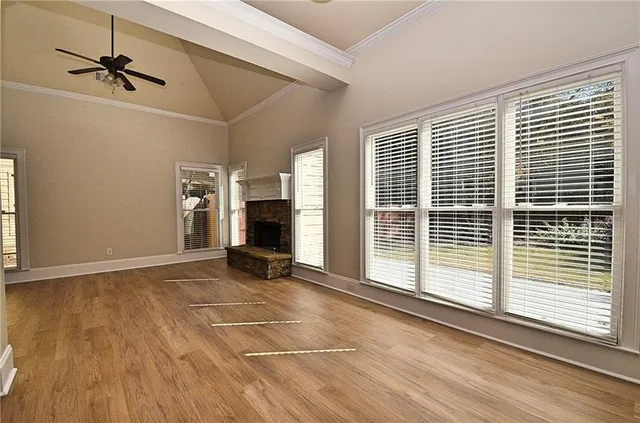 a view of an empty room with a window and wooden floor