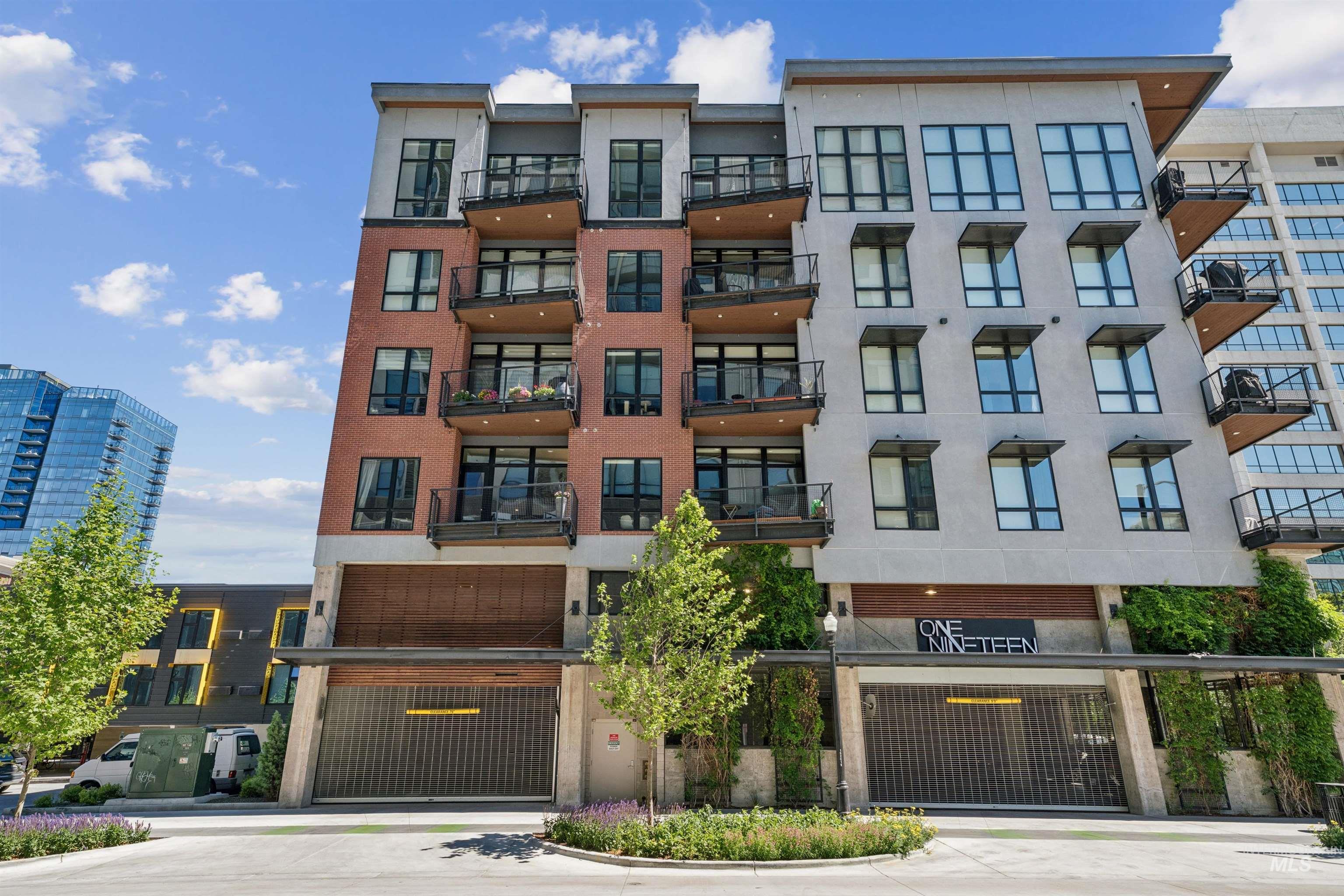 119 South 10th Street, Unit 307 Boise, ID 83702 - Photo 42 of 47 Contemporary multi-story building featuring a brick and light-colored facade, multiple private balconies with dark railings, large windows, and ground-level garage access
