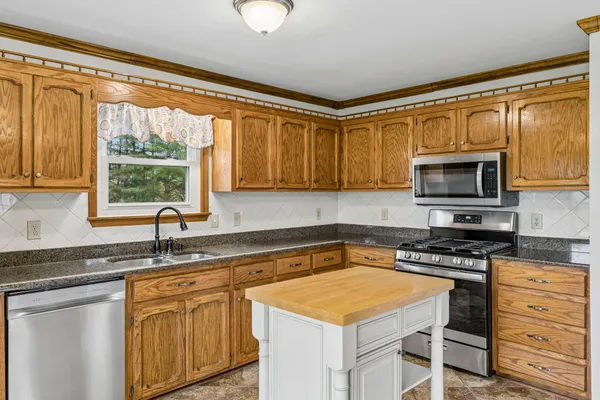a kitchen with granite countertop a sink appliances cabinets and a counter top space