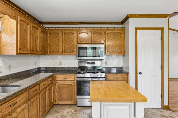 a kitchen with kitchen island granite countertop a sink and a stove next to a window