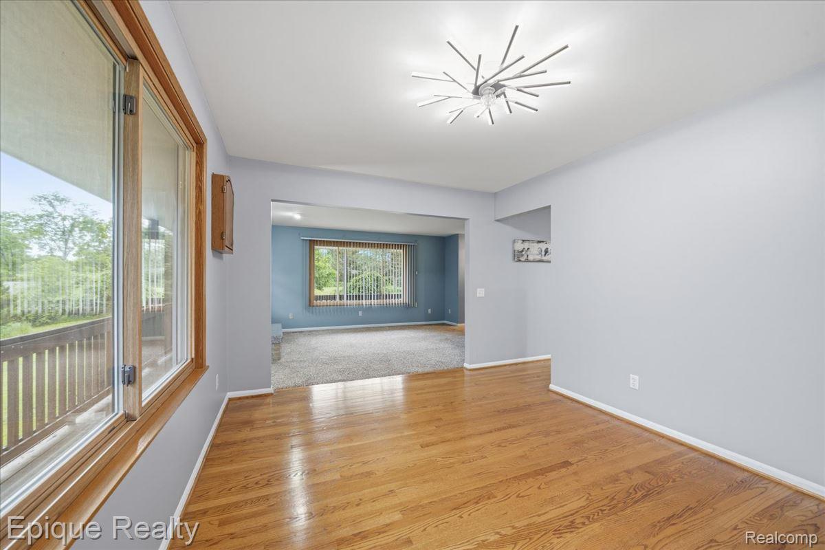 1221 Rhodes Road Lake Orion, MI 48360 - Photo 20 of 72 Hardwood flooring extending into an archway, large windows with wood trim, contemporary ceiling light fixture, and light gray wall paint